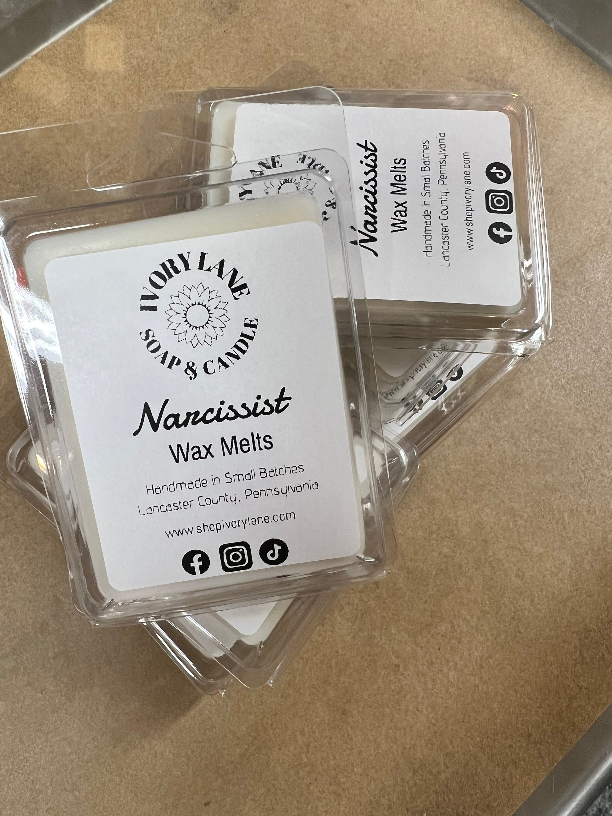 Wax melts packaging with 'Narcissist' branding on a beige surface
